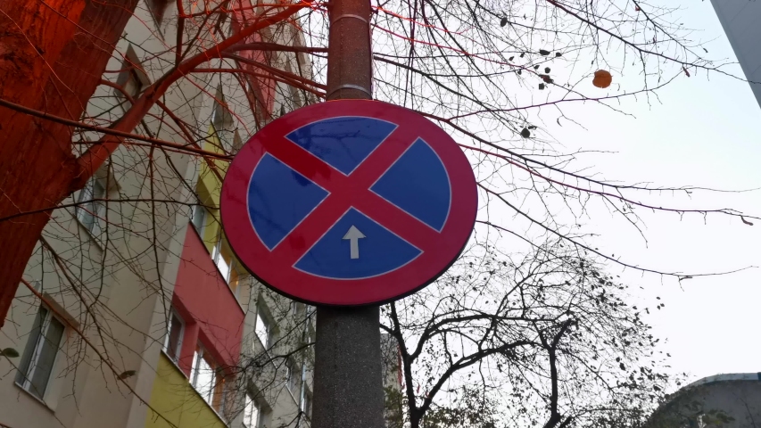 Car stopping prohibited sign mounted on a pillar, parking forbidden, neighborhood, building, camera pan over sign