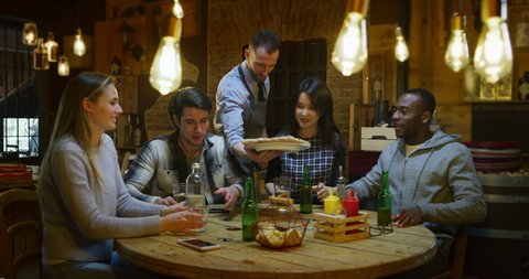Slow motion of friends are served by a waiter with italian pizza and drinking beer at restaurant or pub. Shot in 8k. Concept of college friends, holidays, food and drink
 – Video có sẵn