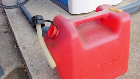 Filling gas can with gasoline. Gasoline pump nozzle and red gas can at petrol filling station.