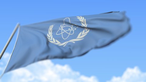 Waving flag of the International Atomic Energy Agency IAEA, low angle view. Editorial loopable realistic slow motion 3D animation