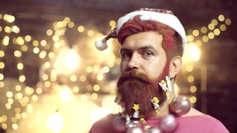 Man New Year eve. Portrait of surprised and funny man. Beard with Christmas decoration. Styling Santa Claus with a long beard posing on the wooden background. Santa in home