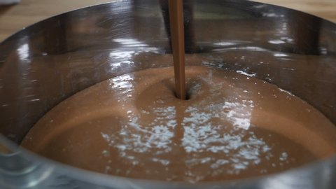 Closeup shot of pouring chocolate cake mixture into tins. Making Chocolate Layer Cake. Culinary concept. Slow motion. Shot in hd