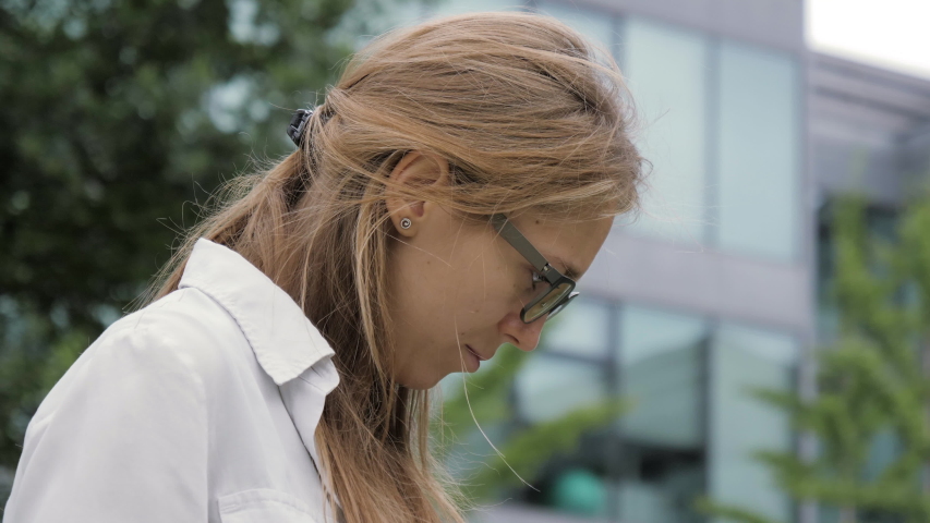 Young woman with glasses looking at the monitor of her lapltop.