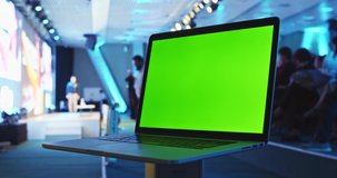 Chroma key laptop pc monitor in public space with people crowd listening to the coach speech on stage in conference meeting hall. Modern university education system. Green screen notebook mock-up.