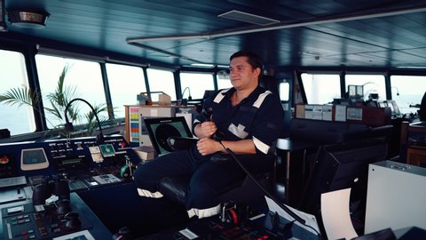 Marine Deck Officer or seaman on navigation bridge of vessel or ship . He is speaking on the VHF radio. Colreg communication