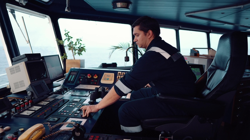 Marine navigational officer during navigational watch on Bridge . He is maneuvering the ship. Work at sea. Royalty-Free Stock Footage #1041943636