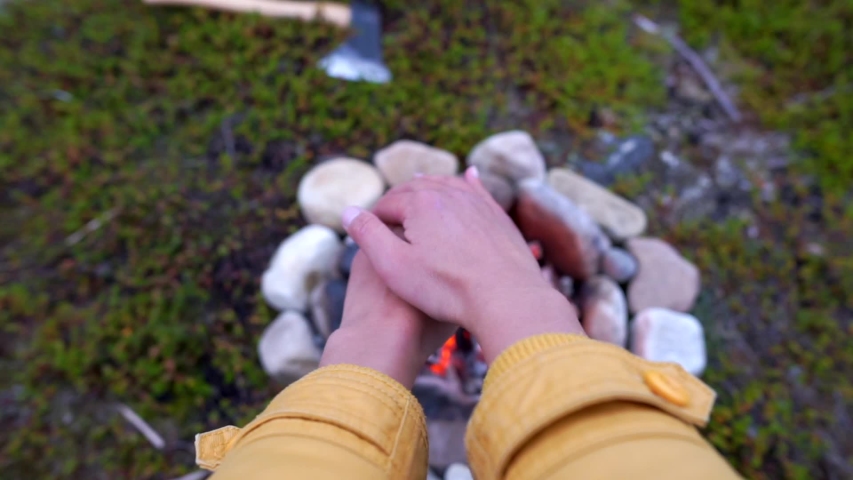 Girl heat hands by campfire