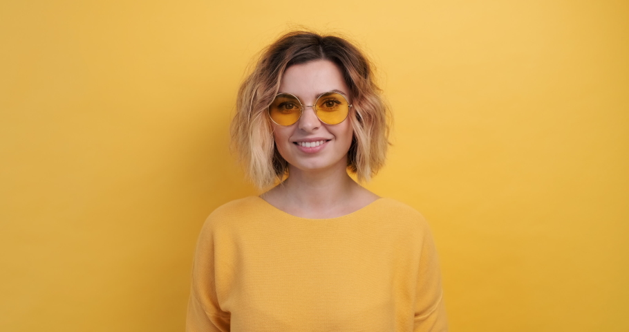 Portrait Happy Woman Smiling Dancing to Music Rhythmically to Beat Moving her Hands in Yellow Sweater Yellow Background Slow Motion in Yellow Glasses . Monotone. Positive Emotions of People. Freedom Royalty-Free Stock Footage #1041950827