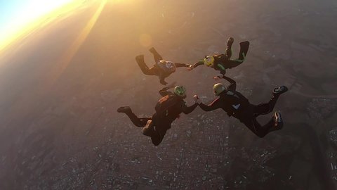 Skydivers make a formation skydive at the sunset