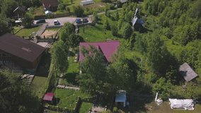 Flying over the small town with beautiful houses with bright pink roofs, trees swaying in the wing and green lawn. Clip. Top view of the ecological place to live.