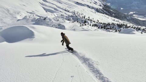 A girl is snowboarding in the backcountry during the winter in Swiss Alps. Shot in 4k with a gimbal.