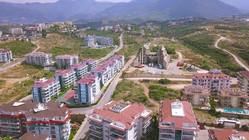 Aerial view of hilly area and houses of the city. Art. Southern town roofs surrounded by green bushes and trees, nature and ecological place to live.
