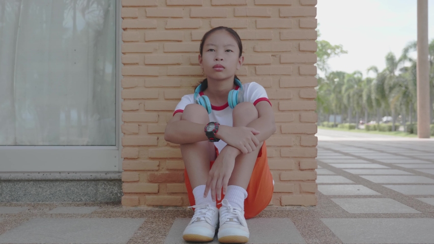Little asian child sitting and waiting someone. Depressed asian girl. 
