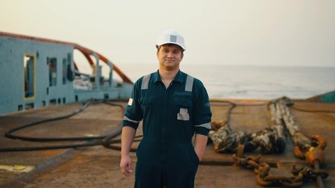 Marine Deck Officer or Chief mate on deck of offshore vessel or ship , wearing PPE personal protective equipment - helmet, coverall. He is looking at the camera