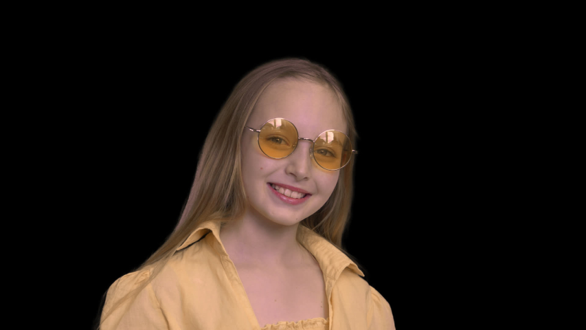 Portrait smiling girl in yellow dress wearing yellow glasses isolated alpha channel. Happy girl teenager on circle yellow sunglasses posing on. Alpha channel | Shutterstock HD Video #1041995947