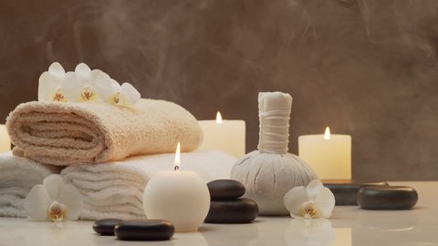 Oriental massage treatment composition. Towel, candles, flowers, stones and herbal balls. Spa procedures, meditation, wellbeing and aromatherapy.