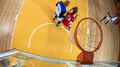 Professional basketball player in action performing slam dunk in a basketball hoop on a sports arena. View from above the hoop.