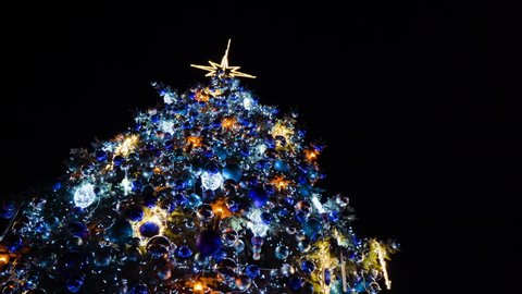 Big glowing decorated christmas tree standing in main market square, winter holidays, peoples enjoy 