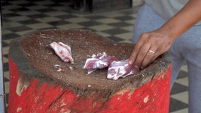 A man is chopping with a cleaver fresh meat of a ram. Man cuts bones for frying
