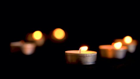 The wind extinguishes candles. Lots of candles with shallow depth. Close-up shot.