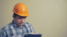 Emotional funny man in a construction helmet with astonishment looks in the documents folder.humorous video portrait of a builder at work