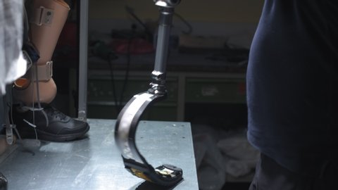 Production of a prosthetic leg. A man creates part of the leg. An engineer is testing the mechanical joint of a prosthetic leg. New sports body part.