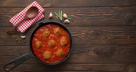 Cooking meatballs with tomato sauce in black pan. Flat lay, top view with copy space