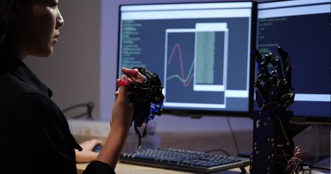 Asian teenage engineer assembling and testing robotics arm responses in laboratory. Student engineer programming controller circuit synchronize technology and collaborating development robot.