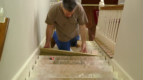 A tradesman or handyman homeowner type fitting in stair riser and measuring for the tread portion of the step.