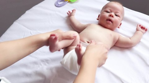 baby gets a massage from the masseuses on the white sheet, foot massage