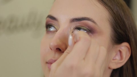 Professional makeup artist puts eye shadow on a client of a beauty salon.