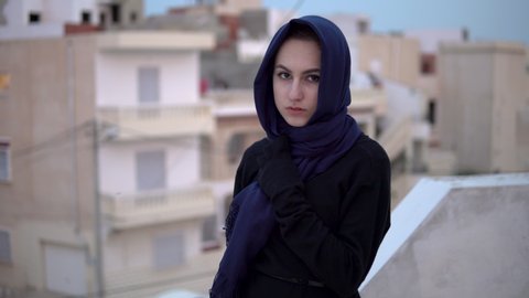 Young woman in arab shawl. A woman is looking at the camera. On the roof of the house against the backdrop of Arab houses.