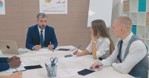 Вirector of the company tells his colleagues new goals and objectives, a startup. Business partners listen to the head of the corporation. Side span of the camera. - Powered by Shutterstock - Get 15% off with code: PIKWIZARD15