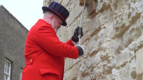 London, UK - April, 2019: The bell ringer rings the bell in the Tower of London, close-up. Compliance with the traditions of British culture. Beefeater in the Tower of London.