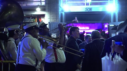 New Orleans/USA October 26th 2019: African american black male is playing the trumpet music with his performance band at night after the rain in the french quarter with crowds of tourist having fun 