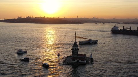 Istanbul Maidens Towers Sunset Sky Aerial. Cargo ship sails into Bosphorus Sea off the Maidens Towers shore. Kiz Kulesi drone footage