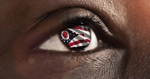 Woman black eye in close up with the flag of Ohio state in iris, united states of america with wind motion. video concept
