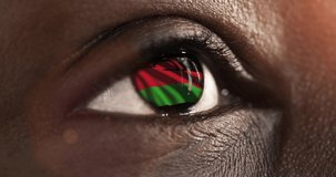 woman black eye in close up with the flag Malawi in iris with wind motion. video concept