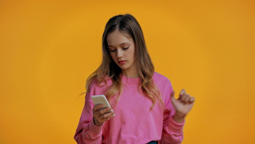 smiling teenager having video call isolated on yellow