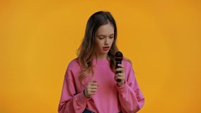 teenager singing with microphone isolated on yellow