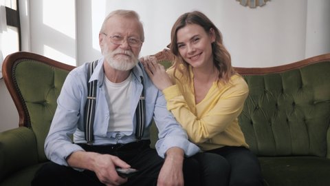 old parents, a happy young daughter and a loving elderly grandfather have fun cute chatting and laughing while sitting on the couch during a family weekend