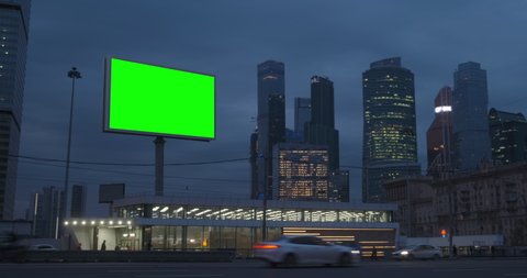 Large billboard with a green screen, a megapolis highway with neon lights, skyscrapers on background, city traffic at night, Moscow Russia