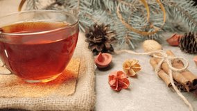 New Year and Christmas decoration. Some pine cones, branches of Christmas tree, cinnamon sticks, ribbons and flowers on a silver texture. A cup with Christmas tea on the table. Close up - Powered by Shutterstock - Get 15% off with code: PIKWIZARD15