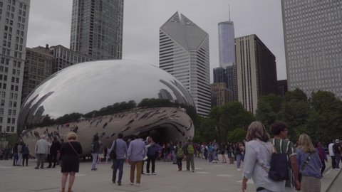 Chicago, USA - Circa 2019: Famous cloud gate art sculpture in downtown park made of steel reflecting cityscape skyline on Chicago bean day time exterior establishing shot skyline in background