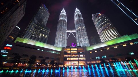 KUALA LUMPUR, MALAYSIA - November 26, 2019: Exotic low angle view of Petronas Twin Towers and Suria KLCC shopping center with beautiful night lights. Shot in 4k resolution