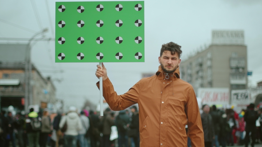 Man hold banner in hand. Tracking points for copy space. Blank green screen board. Human rights. Crowd people day demonstration. Rebel strike protest. Revolution in city street. Political rally 4k. Royalty-Free Stock Footage #1042073776