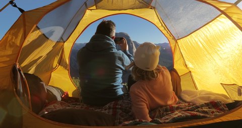 The view from the back on the couple sitting together in a tent and admiring the beauty of Yosemite Valley against the background of the central part of the Sierra Nevada ridge and Half Dome rock. 4k