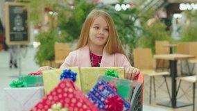 Girl walk in the shopping mall with Christmas present boxes in cart child family attractive teenager beautiful children cheerful happiness holiday kid smiling childhood slow motion