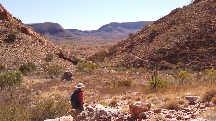 POV following of active tourist woman in Larapinta Trail, Ormiston Pound Walk overlooking Mount Sonder and Gosses Bluff crater. Tourism in Northern Territory, Central Australia, West MacDonnell Ranges