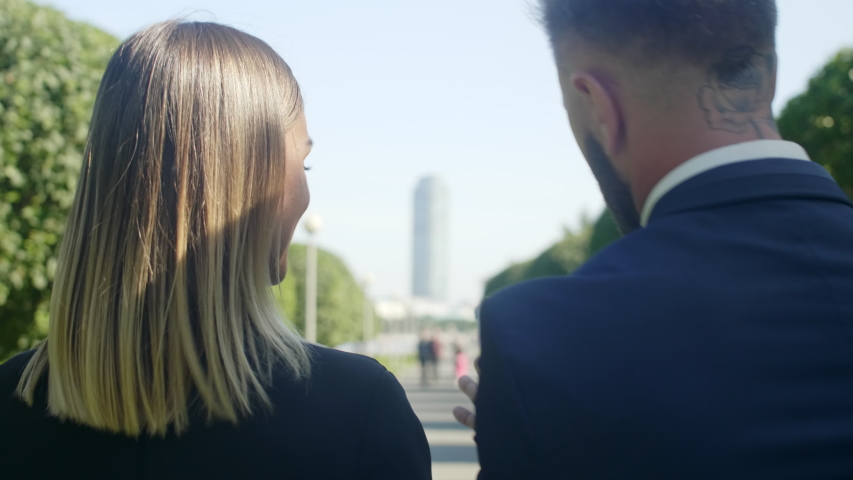 Rear view shot of business colleagues walking through the street with tablet computer and discussing schedule